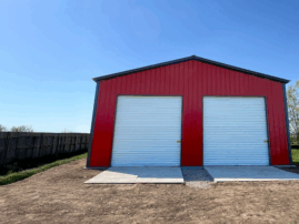 A red two-car metal garage in Abilene, Texas, featuring white roll-up doors and a durable steel structure built by American Steel Carports, Inc.