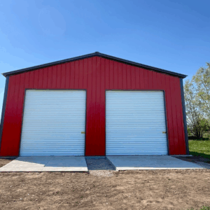 A red two-car metal garage in Abilene, Texas, featuring white roll-up doors and a durable steel structure built by American Steel Carports, Inc.