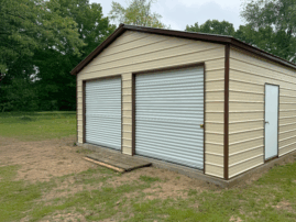 Pebble beige two-car metal garage with earth brown trim, white roll-up doors, and a side walk-in door, installed in Albany, KY by American Steel Carports, Inc.