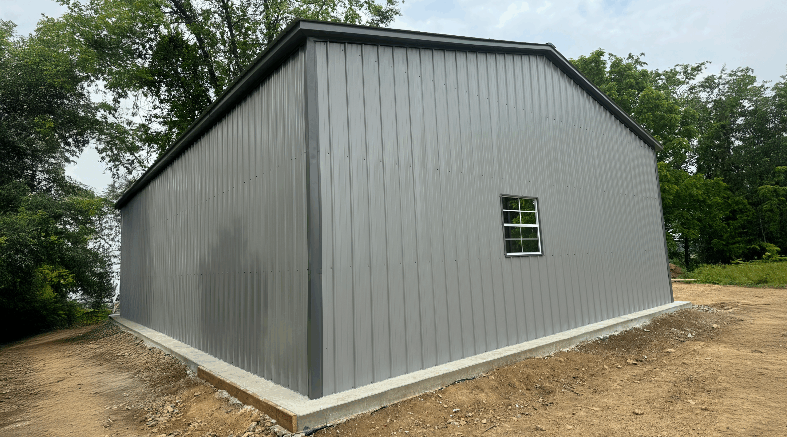 Side view of a gray clear span metal garage with a single window and clean vertical siding, built in Albert Lea, Minnesota by American Steel Carports, Inc.