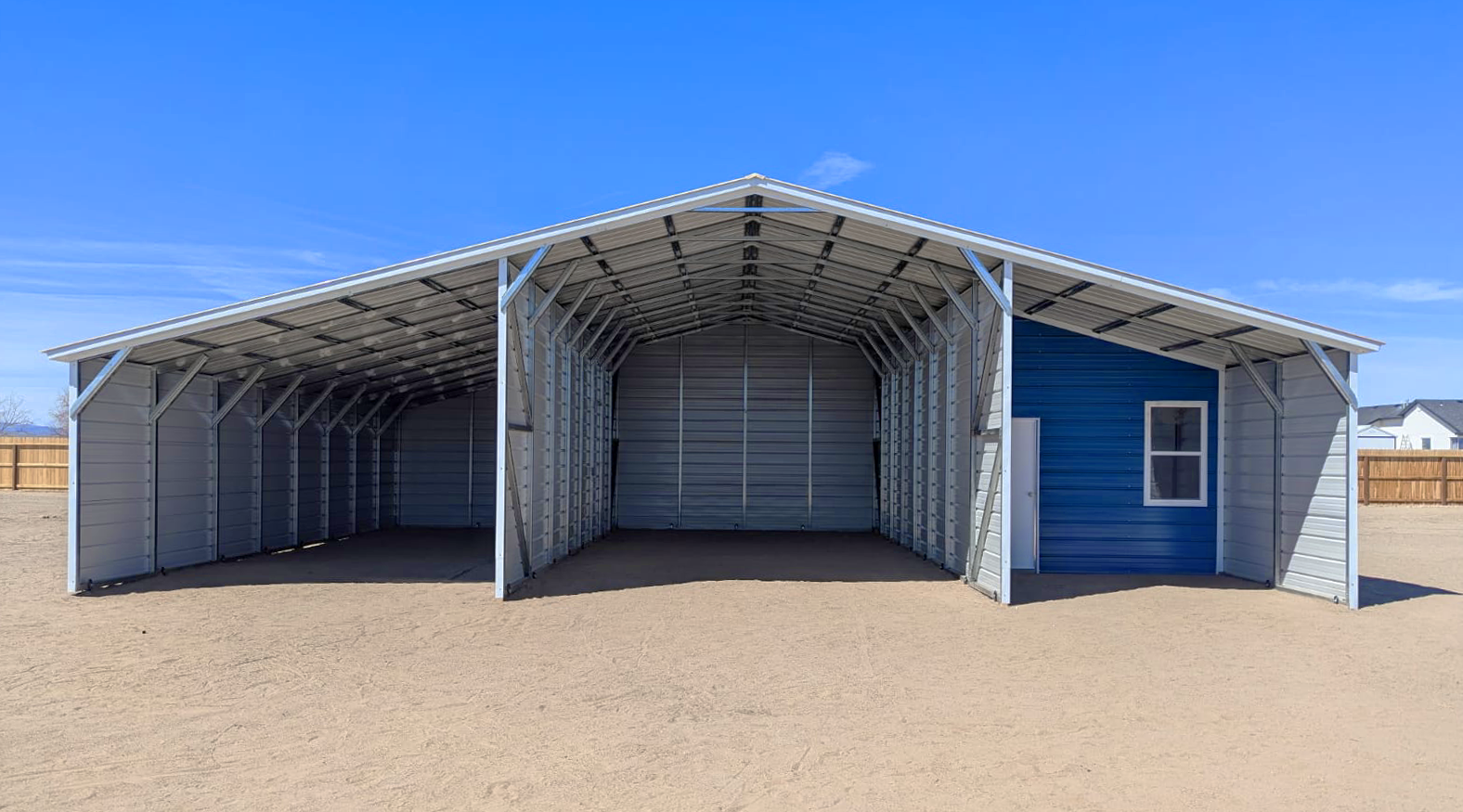Front view of a metal barn in Arlington Heights, IL with a center enclosed garage, open lean-to sections on both sides, and a blue accent wall with a walk-in door and window.
