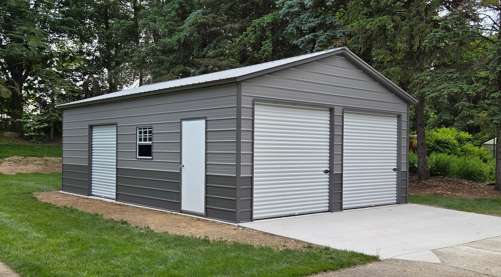 Side profile view of a pewter gray steel garage in Appleton, WI with walk-in door and two windows, installed by American Steel Carports, Inc.