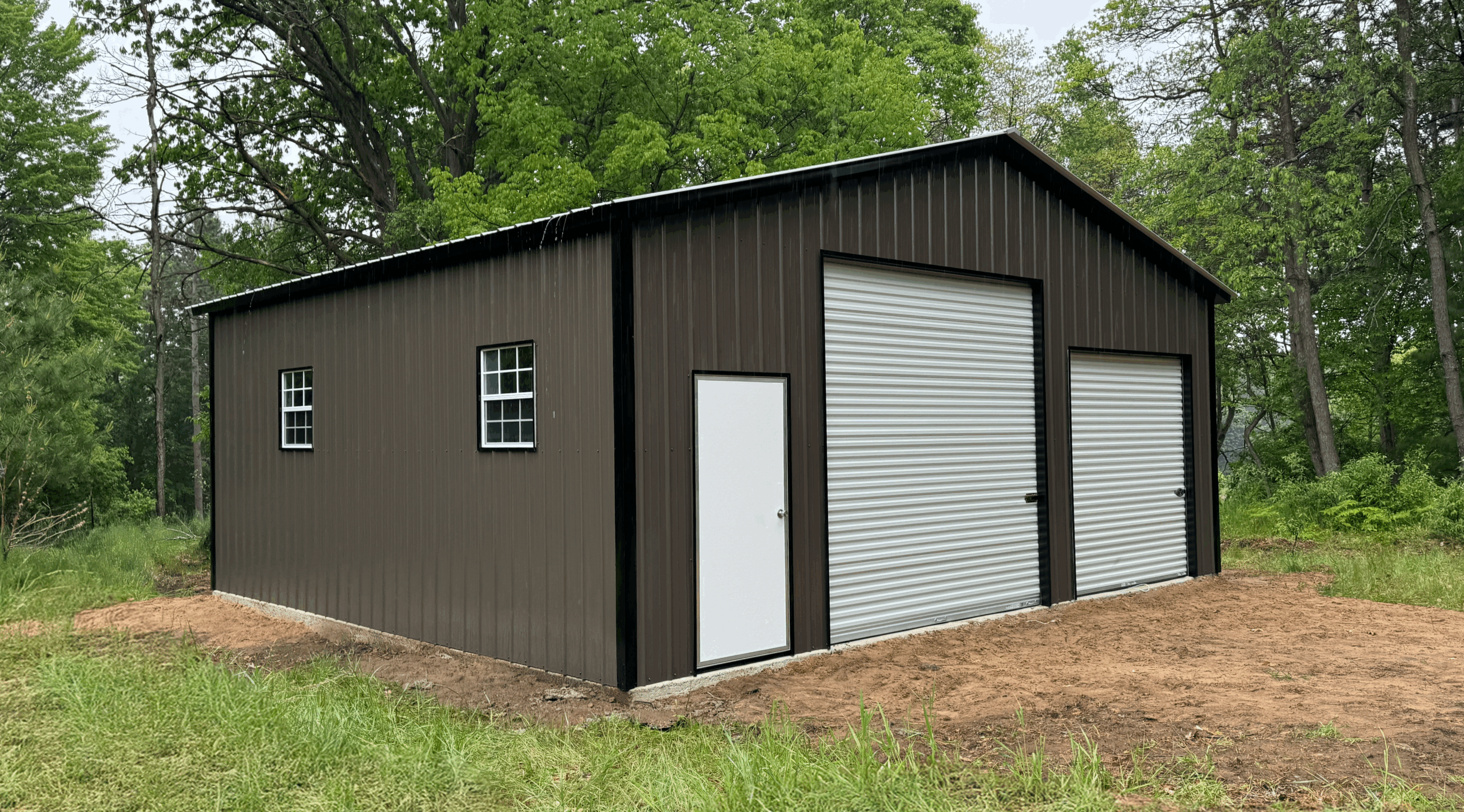 Side profile of a burnished slate metal garage in Allen, TX showing vertical siding and a windowed wall, installed by American Steel Carports, Inc.