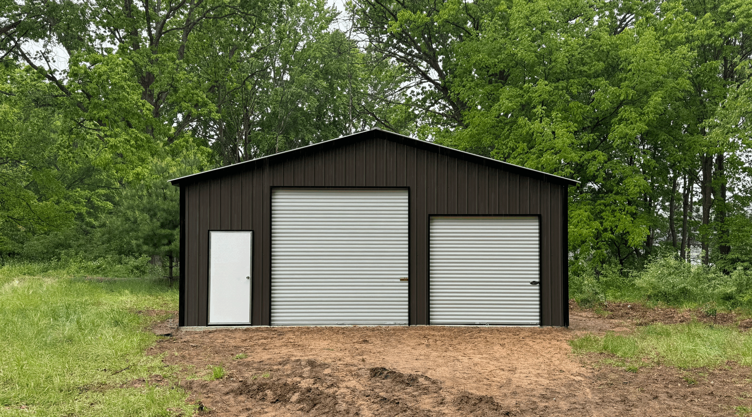 Front view of a burnished slate two-car metal garage with white roll-up doors and a walk-in entry, installed in Allen, Texas by American Steel Carports, Inc.