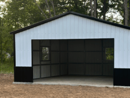 Front view of a white and black two-car metal garage with an open bay and walk-in door, installed in Alto, Texas by American Steel Carports, Inc.
