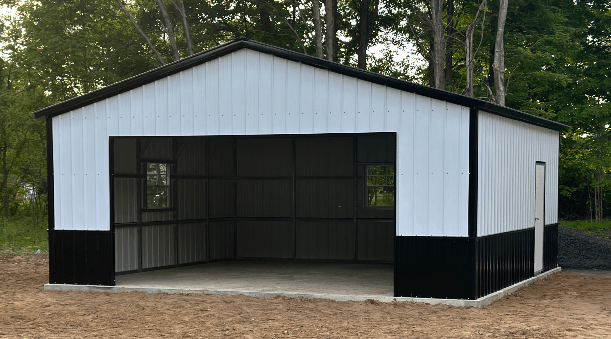 Front view of a white and black two-car metal garage with an open bay and walk-in door, installed in Alto, Texas by American Steel Carports, Inc.