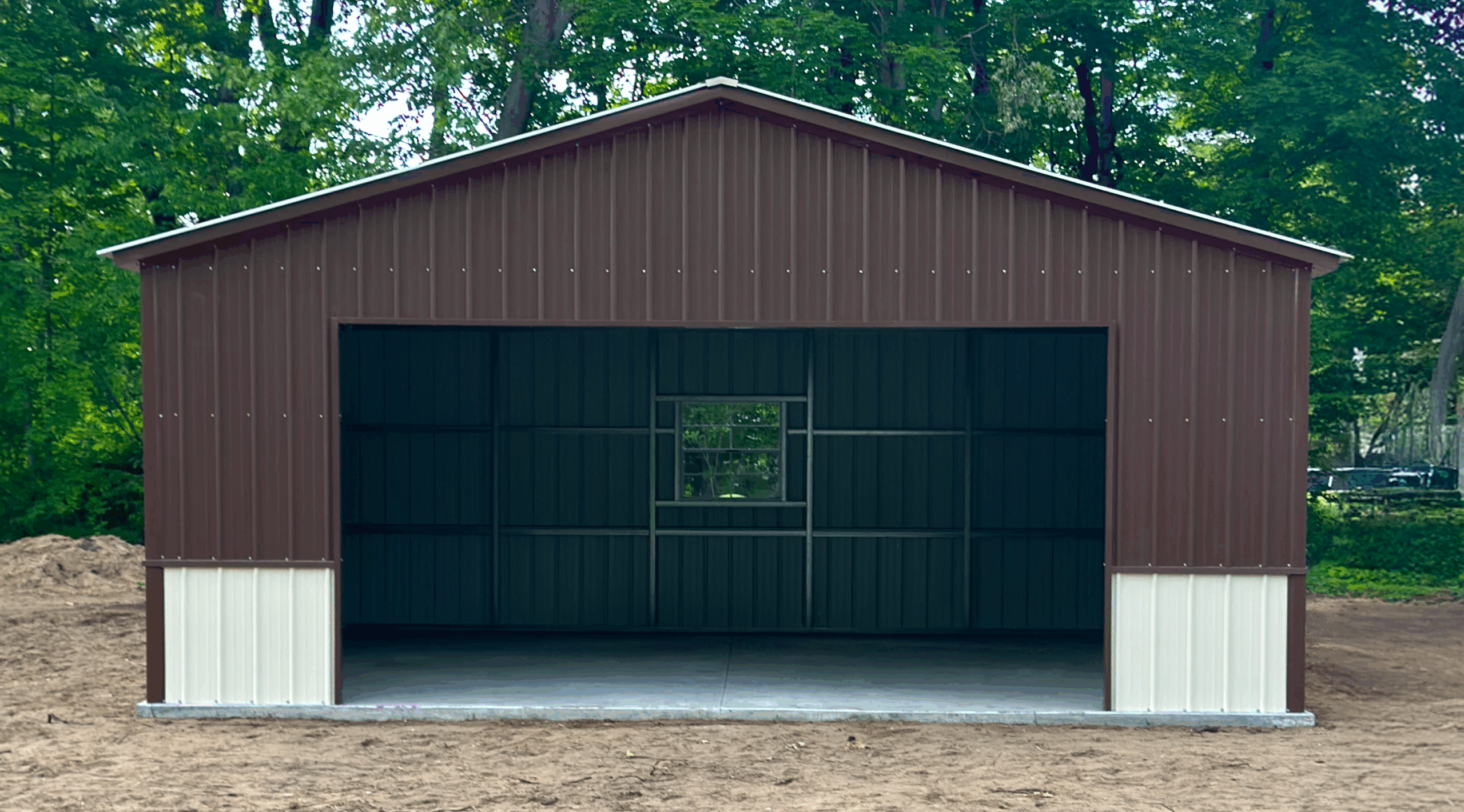 Front view of a two-tone metal garage in Ames, IA with earth brown upper panels, pebble beige lower panels, and a centered window, built by American Steel Carports, Inc.